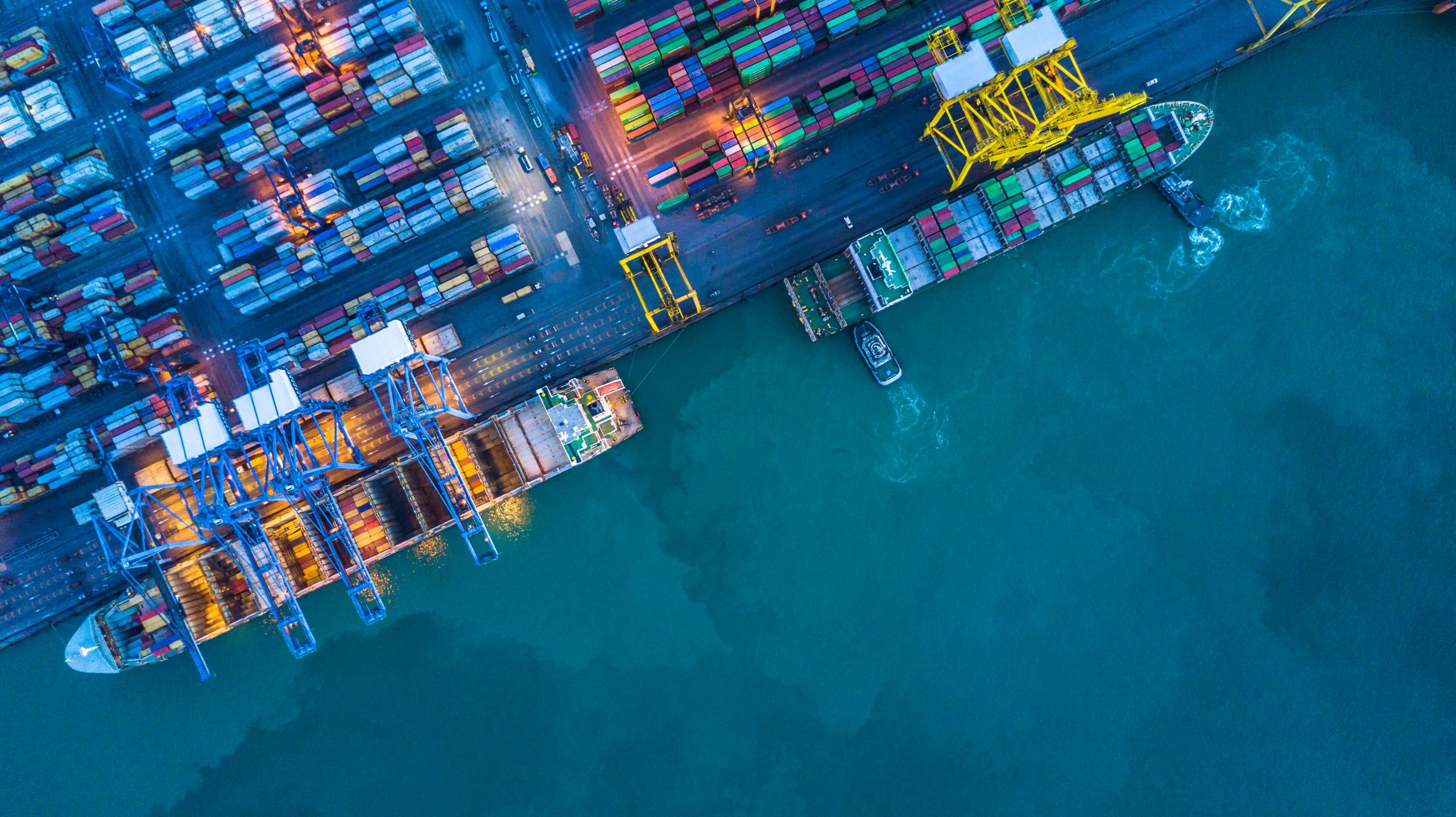 Aerial view of maritime container terminal with vessels docked for cargo loading and unloading.