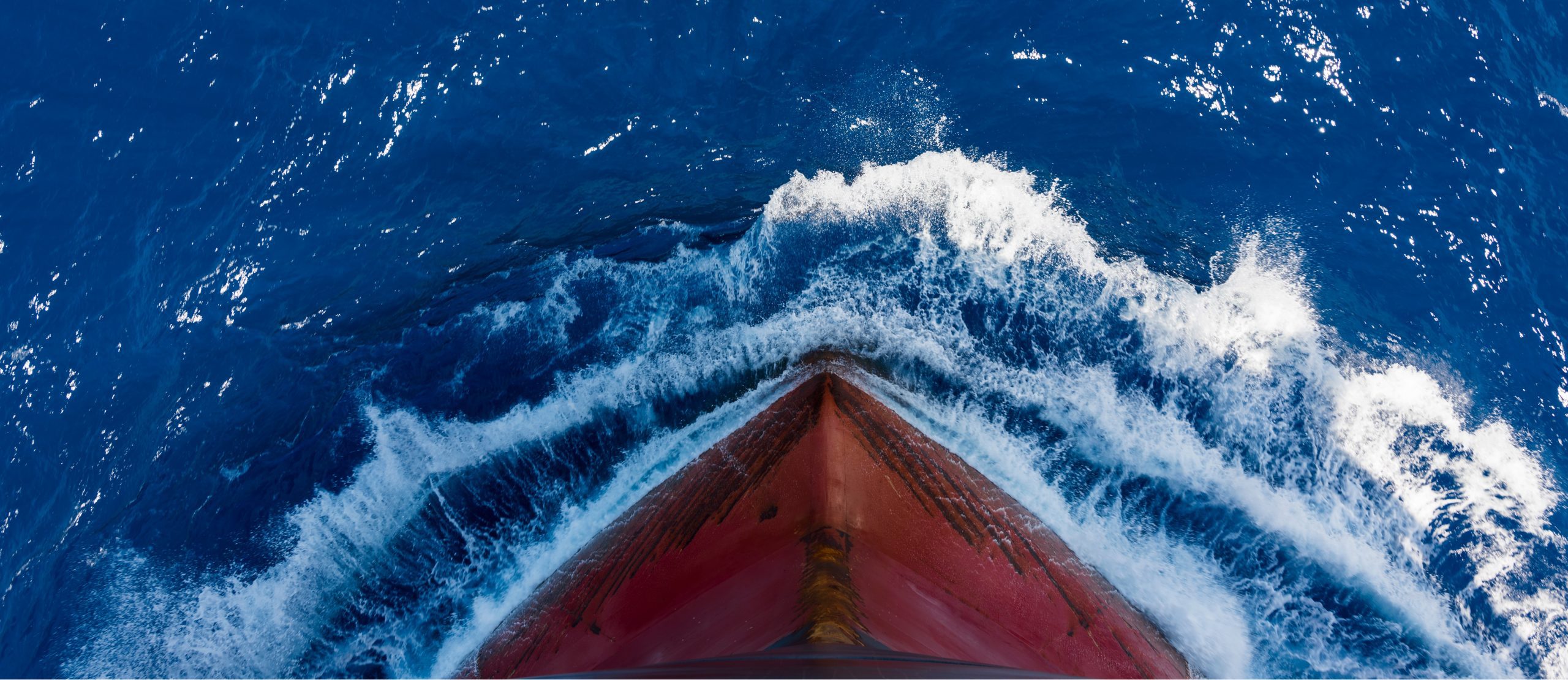 Aerial view of ship bow cutting through ocean water, symbolising vessel propulsion and hydrodynamic efficiency